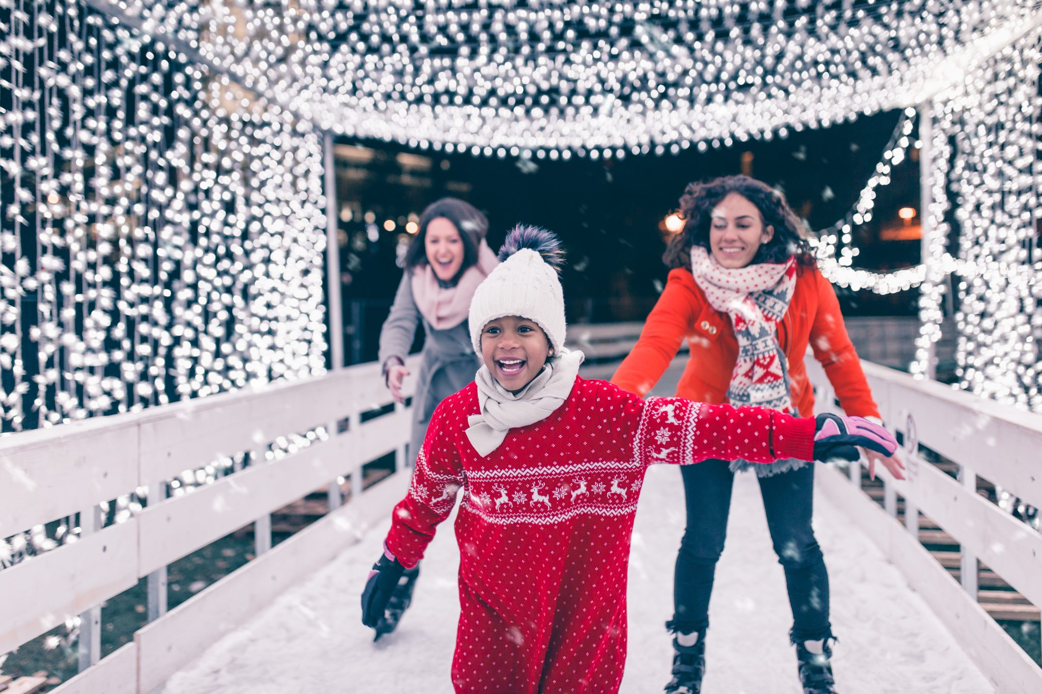 Mother with her daughter and friend enjoying ice skating.