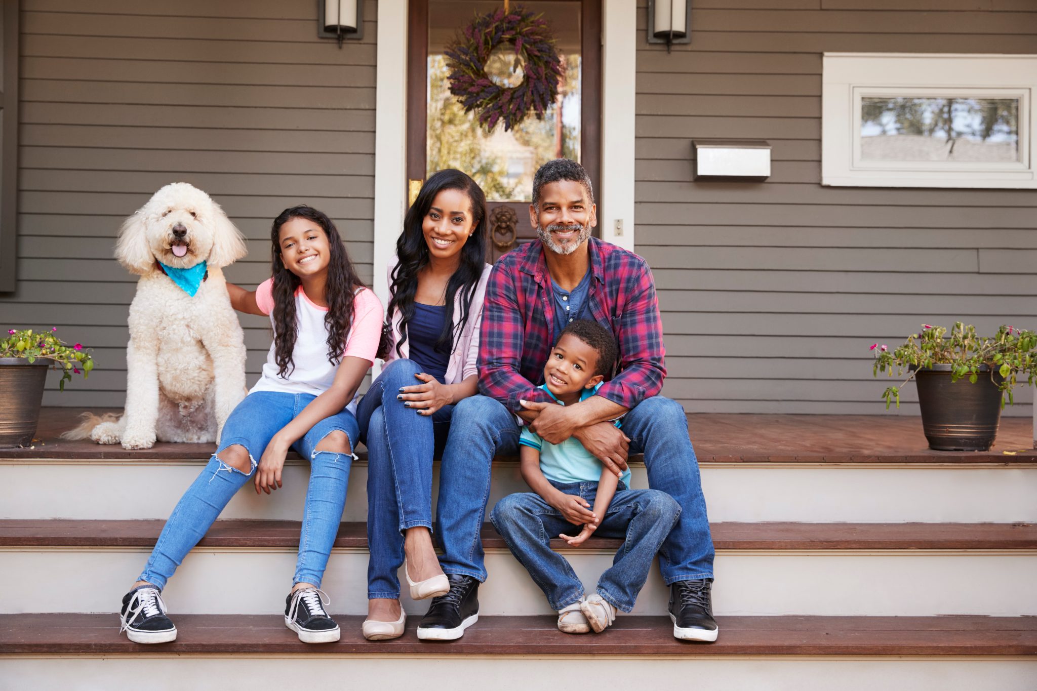 Family With Children And Pet Dog Sit On Steps Of Home in New York