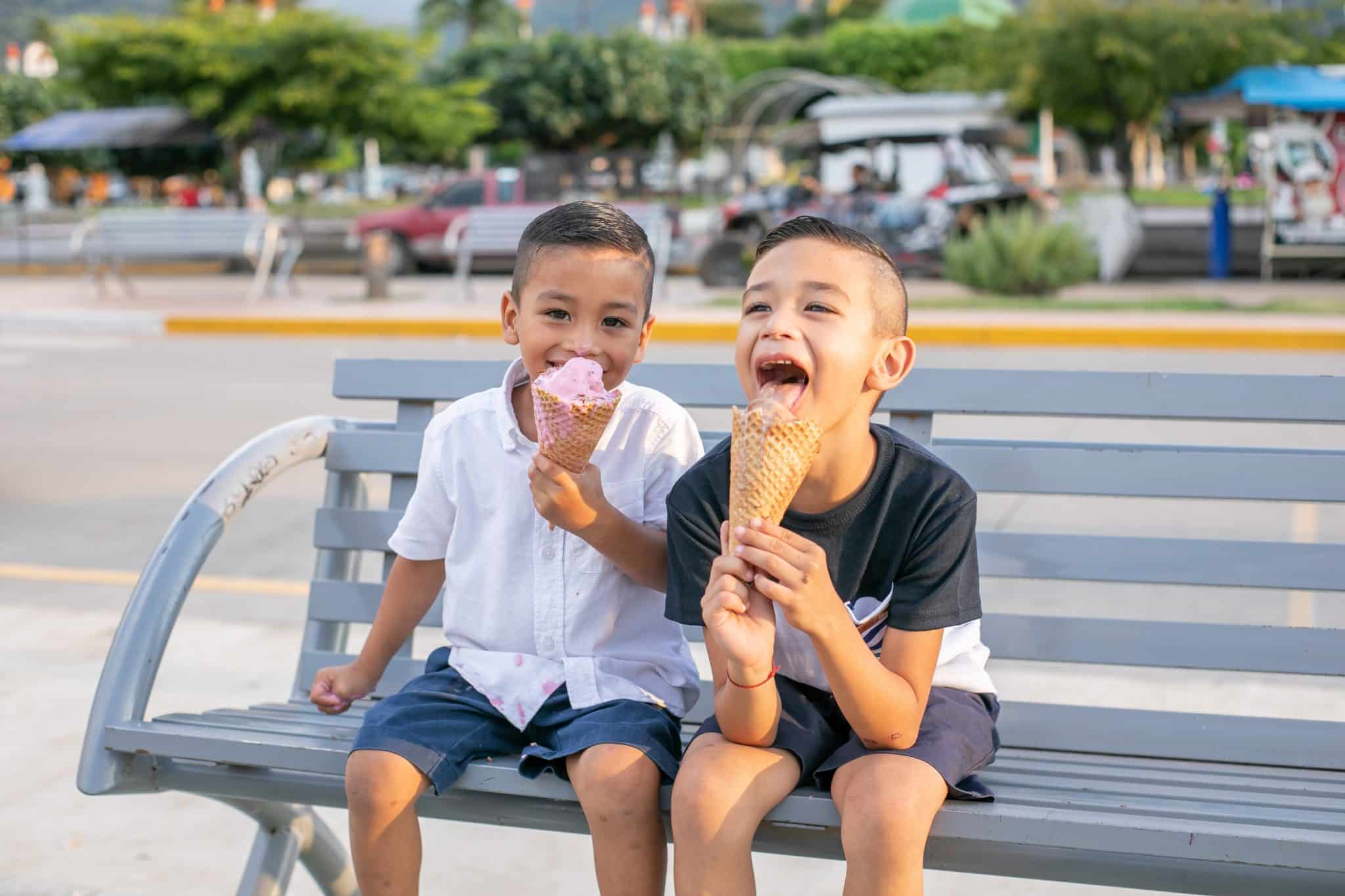Kids enjoying ice cream on a park bench