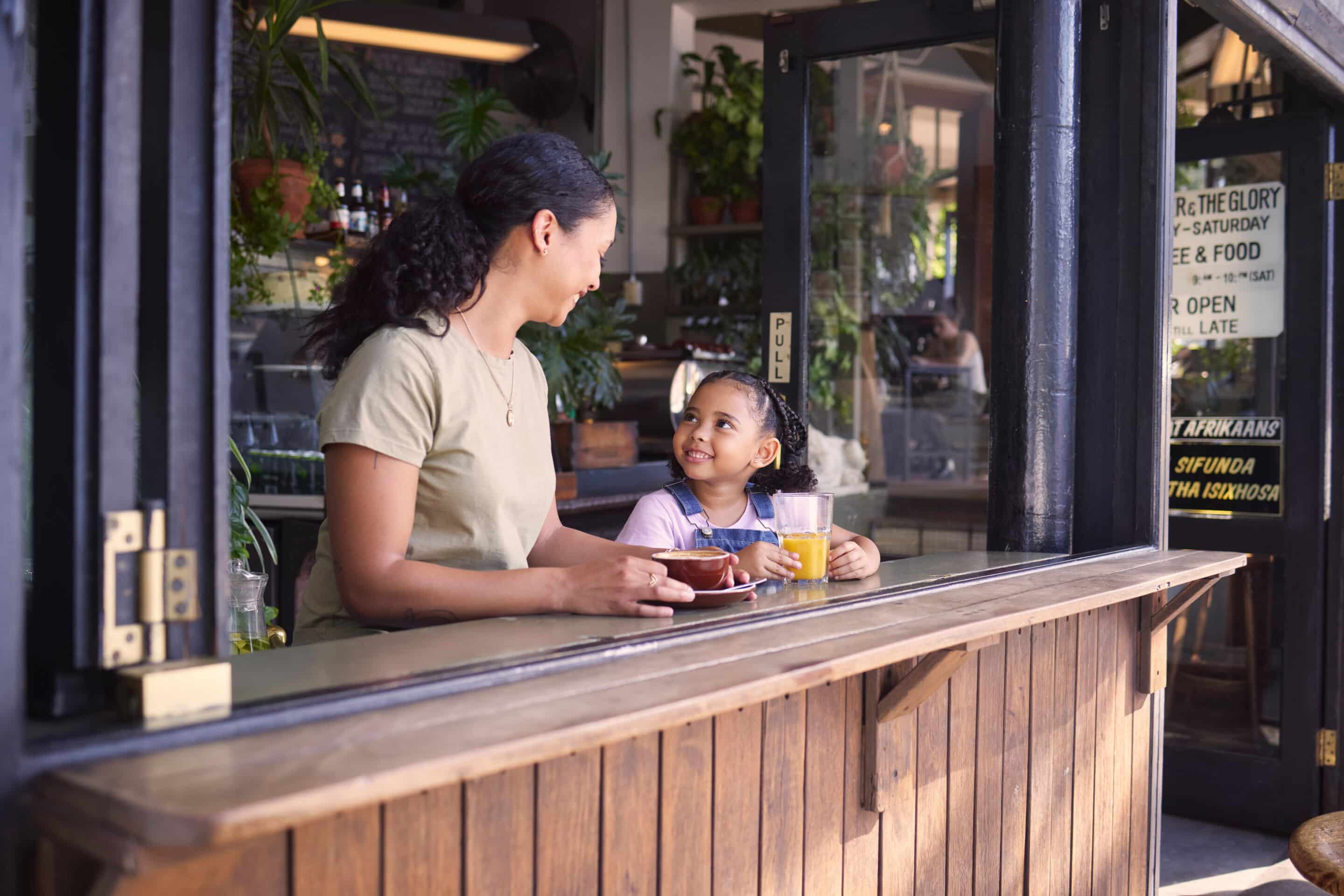 Mother and daughter enjoying coffee and juice together at a café in the suburbs