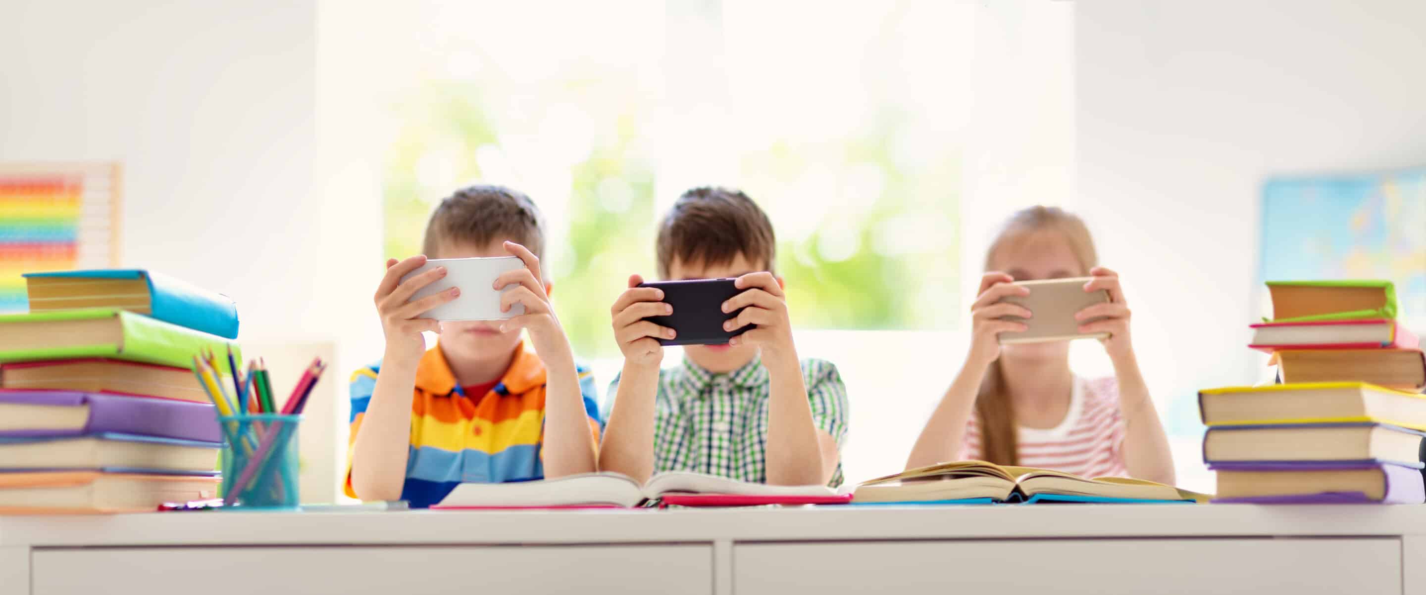 Children in a classroom using smartphones during school activities