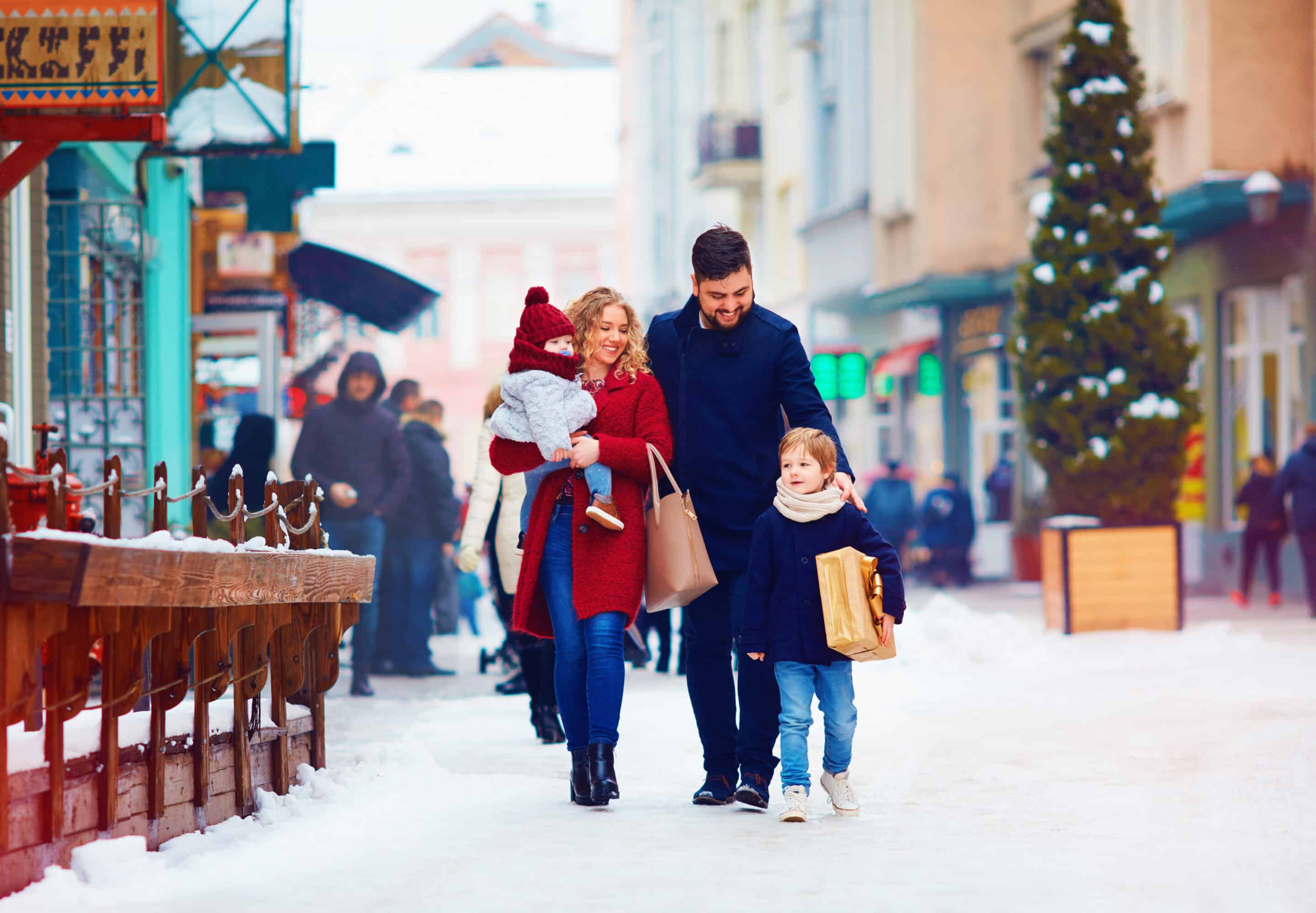 Family walking through a snowy downtown street during the holiday season