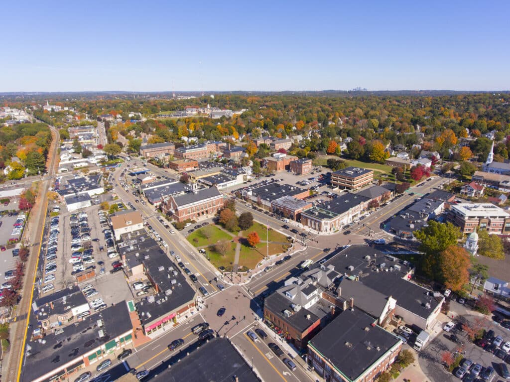 Aerial view of downtown Needham, Massachusetts, with shops, streets, and fall foliage