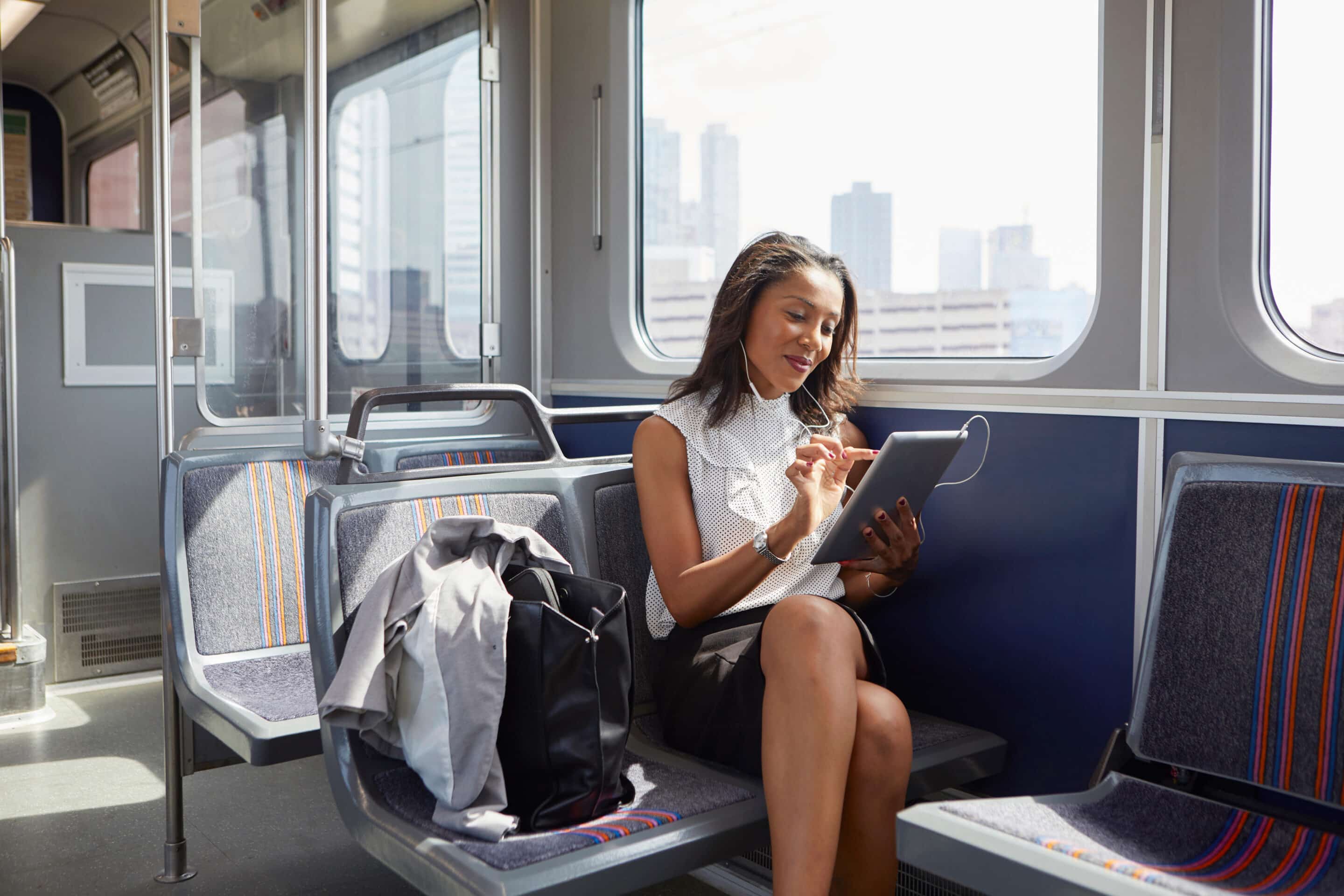 Woman commuting on New Jersey train with tablet Find the right route from the NJ suburbs to NYC.