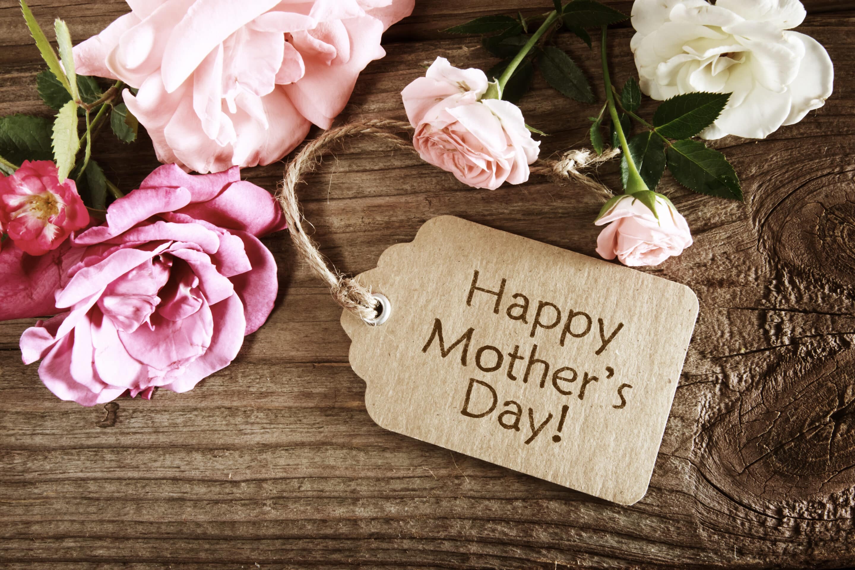 Happy Mother’s Day Mother’s Day card surrounded by pink and white flowers on a wooden table
