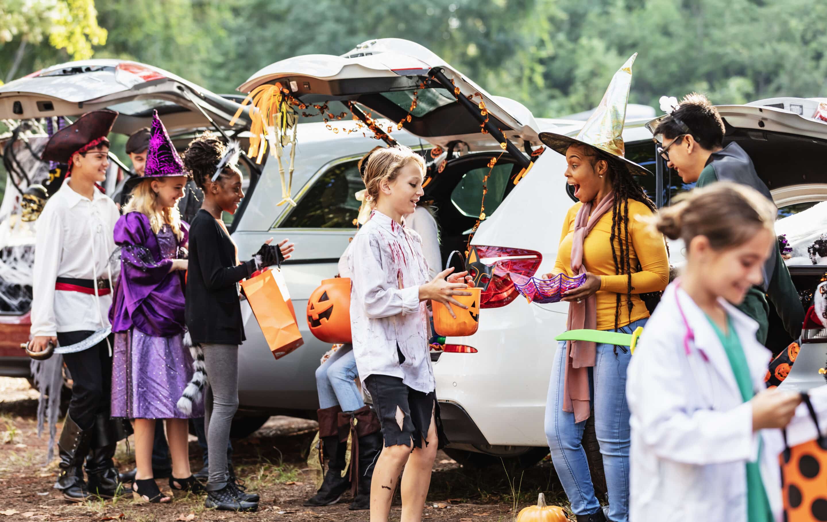 Halloween Trunk-or-Treat in the Suburbs Children dressed in Halloween costumes enjoy a trunk-or-treat event with decorated cars and candy stations.